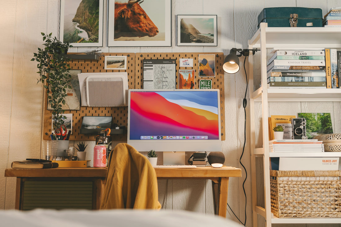 Warmly lit desk with a pegboard wall, plants, books and a small lamp