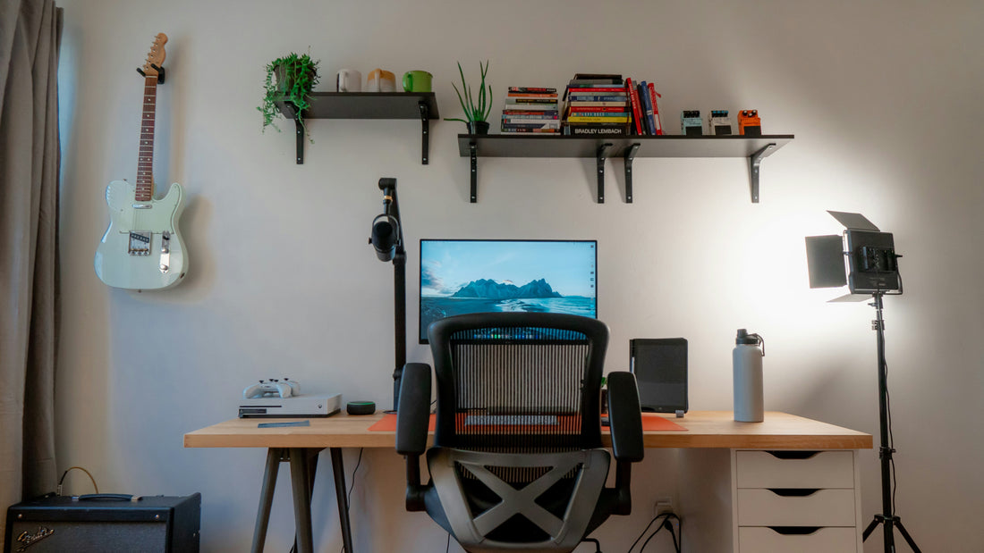 Home studio desk with a guitar on the wall, a shelf and a studio light