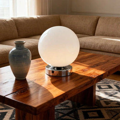 Round glass table lamp glowing on a bedroom nightstand