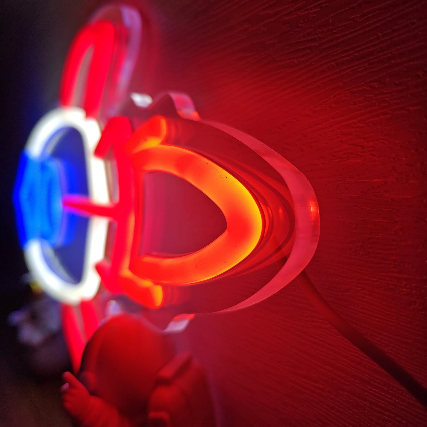 Neon sign with red and blue colors on a textured wall.
