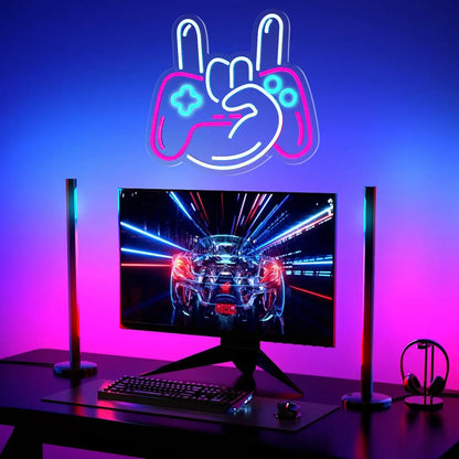 Gaming setup with monitor, keyboard, and neon sign above on a blue and pink gradient background