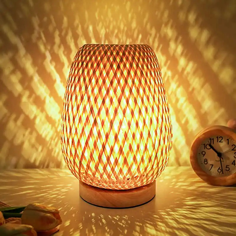 Hand knitted bamboo bedside lamp lit on a wooden table
