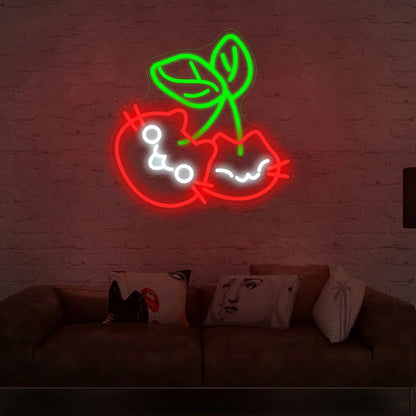 Neon sign of a cherries design on a brick wall above a couch with pillows.