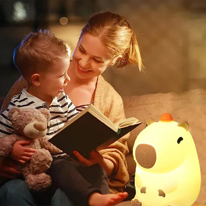 Woman reading a book to a child with a glowing night light in the foreground