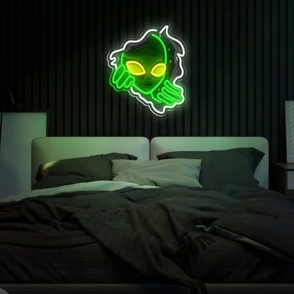 Neon sign of a skull with green and yellow colors on a dark wall above a bed.