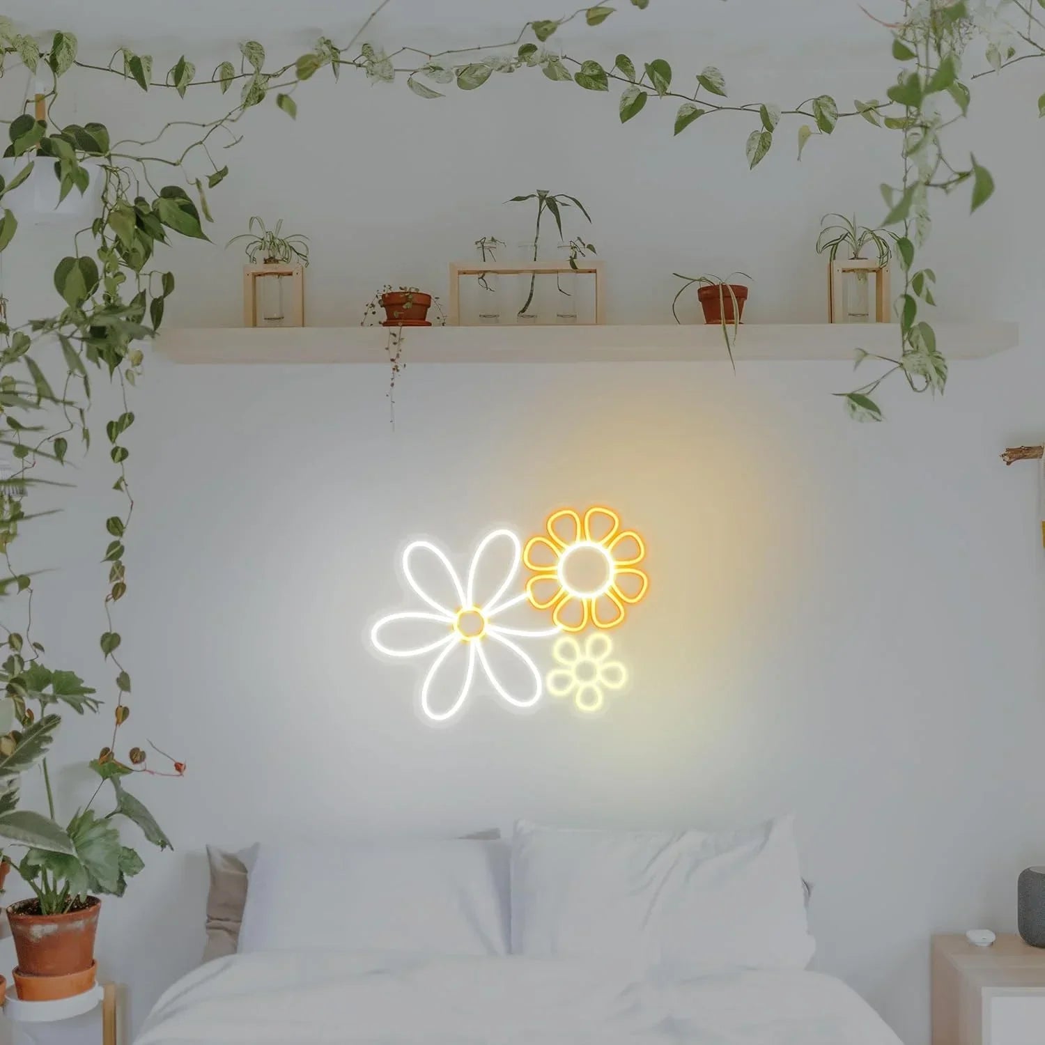 Neon flower lights on a wall above a bed with plants around