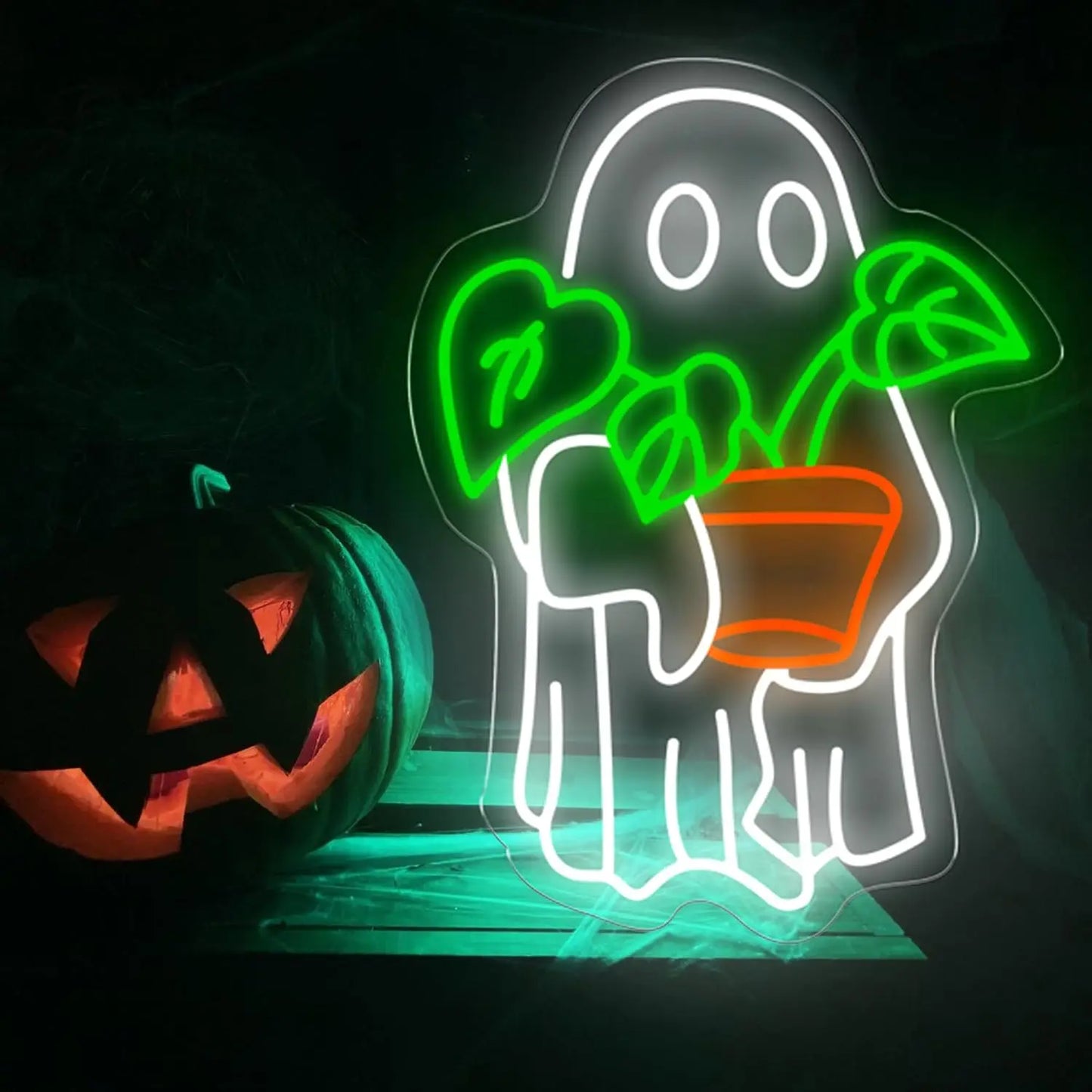 Neon sign of a ghost holding a plant next to a carved pumpkin on a dark background