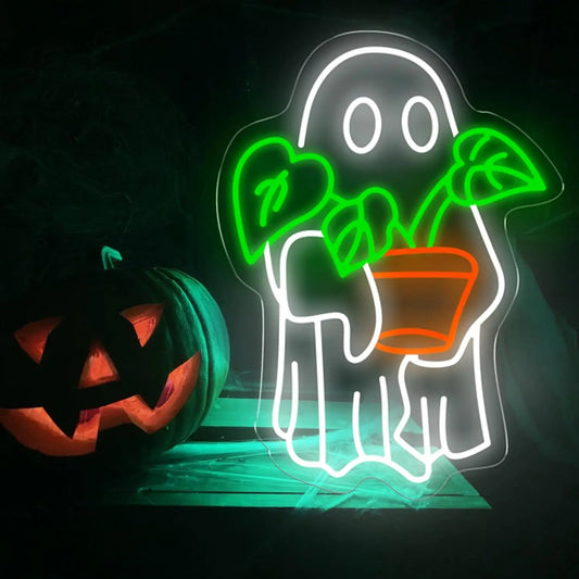 Neon sign of a ghost holding a plant next to a carved pumpkin on a dark background