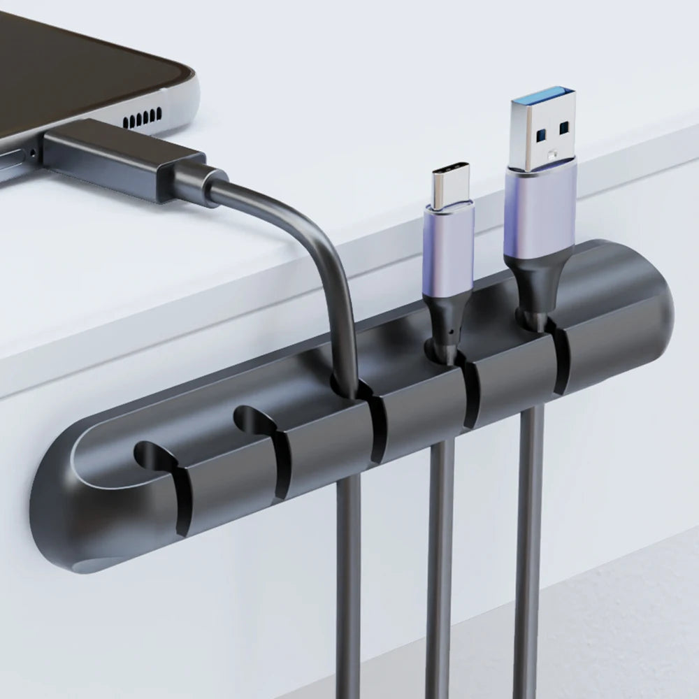 Adhesive cable clips holding charging cables on a desk edge