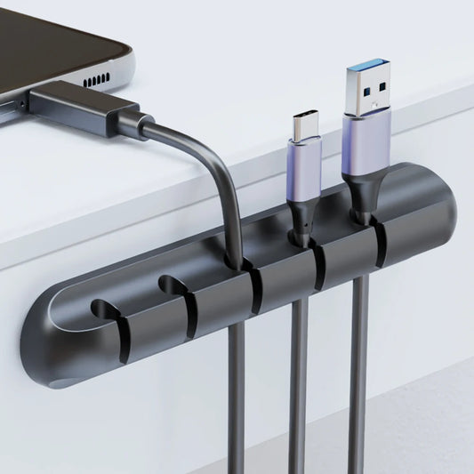 Adhesive cable clips holding charging cables on a desk edge
