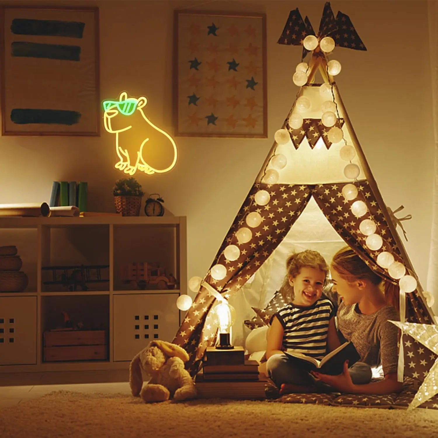 Children playing inside a lit teepee in a cozy room with a neon sign and bookshelf.